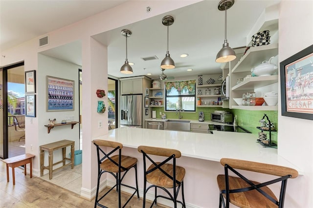 kitchen featuring kitchen peninsula, a kitchen breakfast bar, stainless steel appliances, sink, and decorative light fixtures