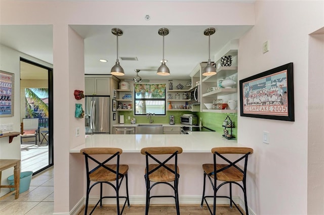 kitchen featuring kitchen peninsula, appliances with stainless steel finishes, a wealth of natural light, and a kitchen breakfast bar