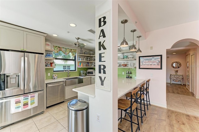 kitchen featuring ceiling fan, sink, stainless steel appliances, pendant lighting, and light hardwood / wood-style floors