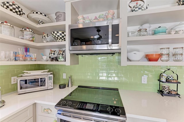 kitchen with tasteful backsplash, white cabinetry, and appliances with stainless steel finishes