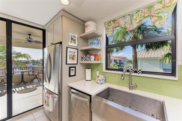 kitchen featuring appliances with stainless steel finishes, backsplash, ceiling fan, sink, and light tile patterned flooring