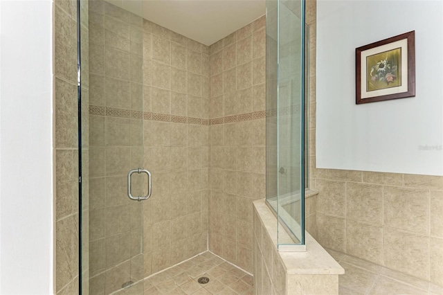 bathroom with a shower with door and tile walls