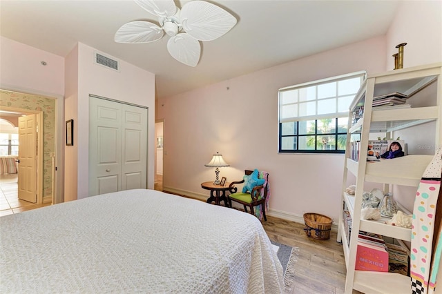 bedroom with multiple windows, ceiling fan, a closet, and light hardwood / wood-style flooring