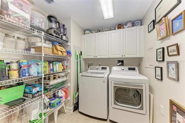 laundry area with cabinets, light tile patterned floors, and washer and dryer