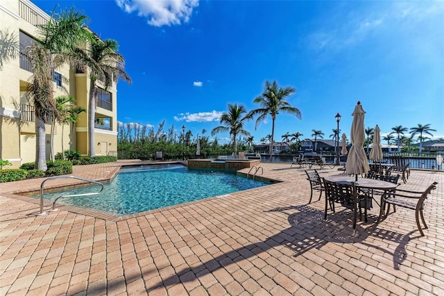 view of swimming pool featuring a patio and a water view