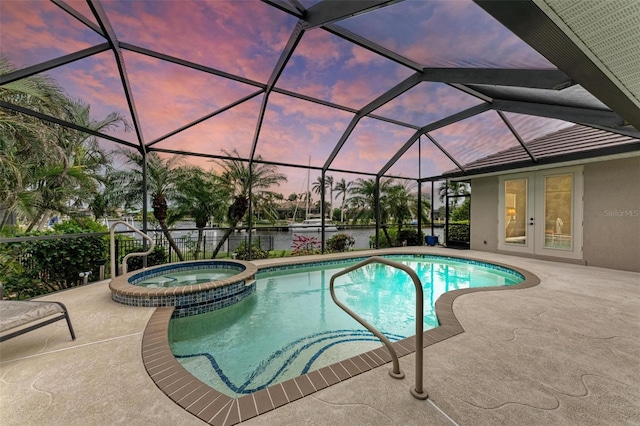 pool at dusk with french doors, a water view, a lanai, an in ground hot tub, and a patio area