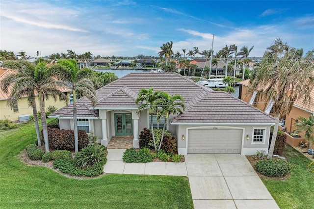 view of front of property with a front yard, french doors, a water view, and a garage