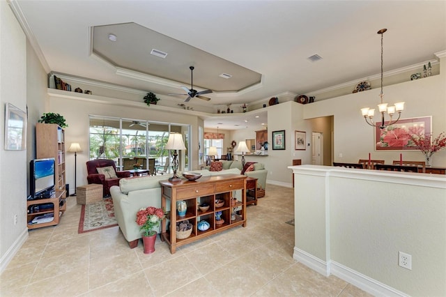 living room with ceiling fan with notable chandelier, a tray ceiling, and ornamental molding