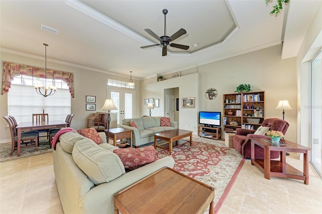 tiled living room featuring ceiling fan with notable chandelier, a raised ceiling, crown molding, and french doors