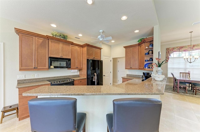 kitchen with ceiling fan with notable chandelier, black appliances, pendant lighting, light tile patterned floors, and a breakfast bar area