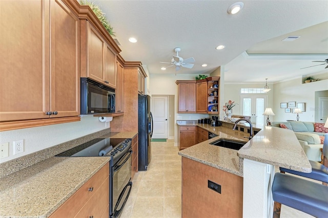 kitchen with a kitchen bar, black appliances, sink, ornamental molding, and light stone counters