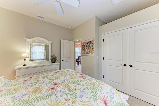 carpeted bedroom featuring a skylight, ceiling fan, and a closet