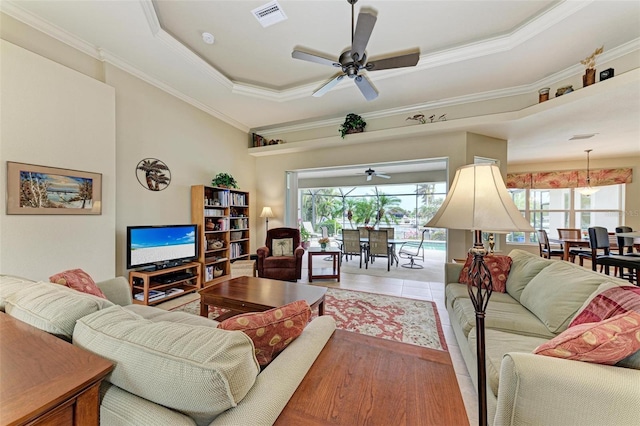 living room with tile patterned floors, plenty of natural light, crown molding, and a tray ceiling