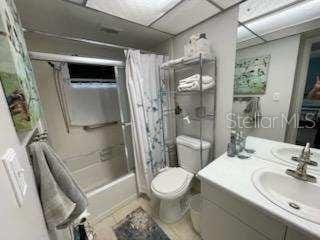 full bathroom featuring a paneled ceiling, vanity, shower / bath combination with curtain, and toilet