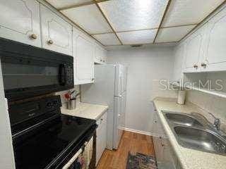 kitchen with white cabinets, light wood-type flooring, sink, and black appliances