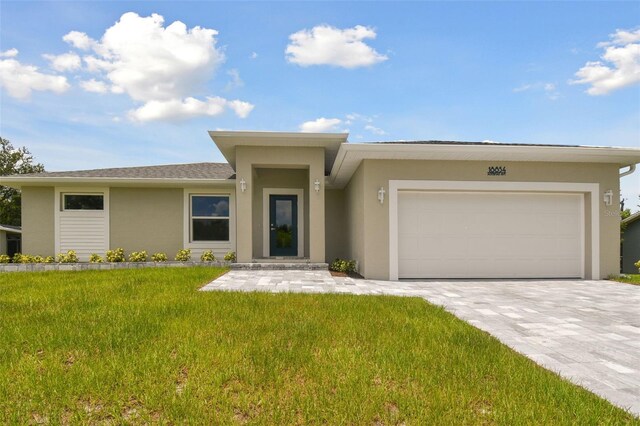 18854 Ackerman Ave, Port Charlotte, FL 33948 - prairie-style house featuring stucco siding, an attached garage, a front lawn, and decorative driveway