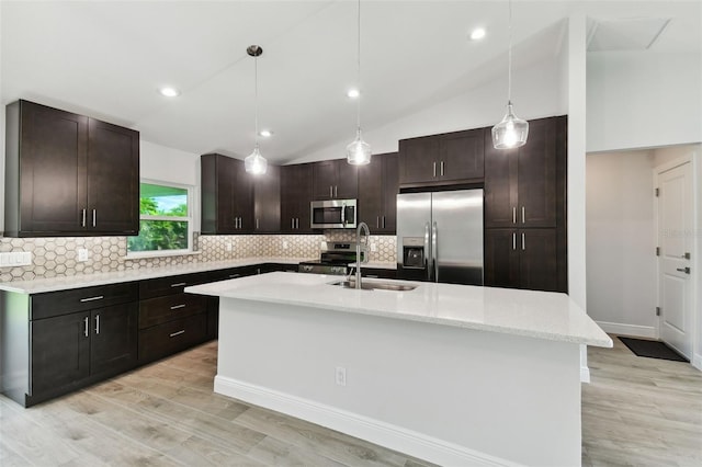 kitchen with a kitchen island with sink, sink, vaulted ceiling, appliances with stainless steel finishes, and dark brown cabinetry