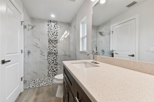 bathroom featuring wood-type flooring, vanity, toilet, and walk in shower