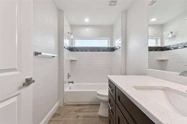 full bathroom with hardwood / wood-style floors, vanity, toilet, and tiled shower / bath