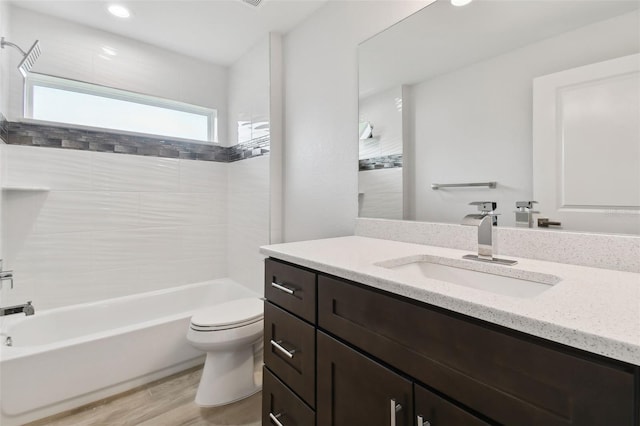 full bathroom with tiled shower / bath, vanity, wood-type flooring, and toilet