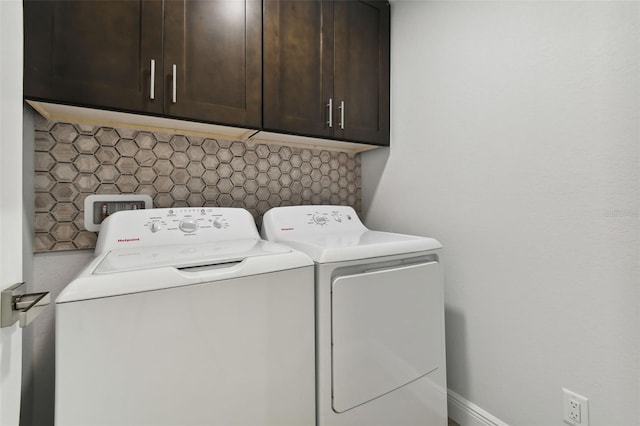 clothes washing area with cabinets and separate washer and dryer