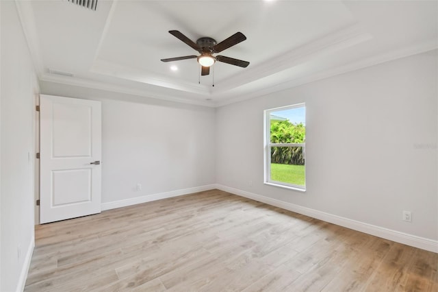 spare room featuring a tray ceiling, crown molding, ceiling fan, and light hardwood / wood-style floors