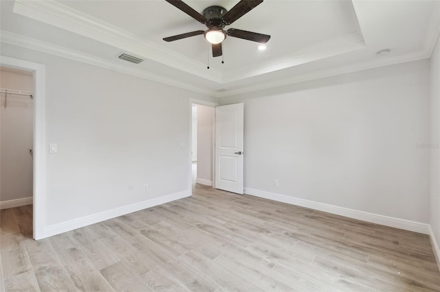 18854 Ackerman Ave, Port Charlotte, FL 33948 - unfurnished bedroom featuring a tray ceiling, a spacious closet, crown molding, light wood finished floors, and a closet