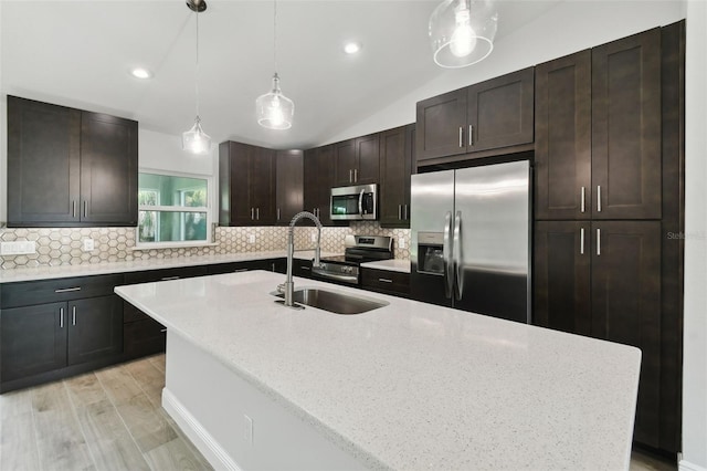 kitchen featuring light wood-type flooring, dark brown cabinets, stainless steel appliances, sink, and an island with sink