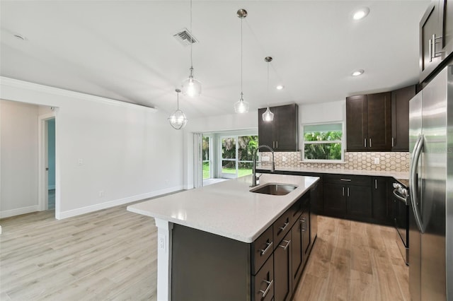 kitchen featuring stainless steel appliances, vaulted ceiling, a kitchen island with sink, sink, and light hardwood / wood-style floors