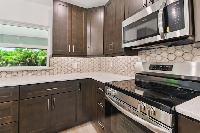 kitchen featuring light stone countertops, appliances with stainless steel finishes, tasteful backsplash, and dark brown cabinets