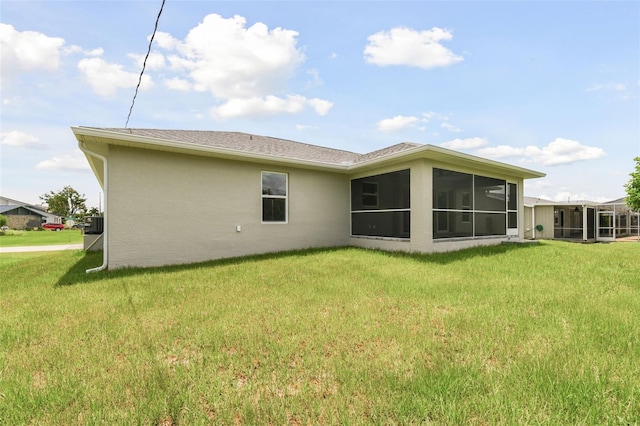 rear view of property featuring a lawn and a sunroom