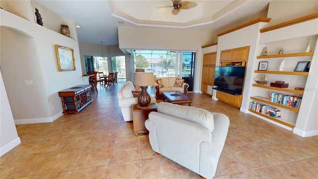 tiled living room featuring ceiling fan, built in features, and a tray ceiling