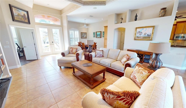 tiled living room with ceiling fan, a towering ceiling, and french doors