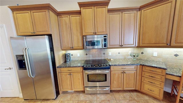 kitchen with decorative backsplash, light tile patterned floors, dark stone counters, and appliances with stainless steel finishes