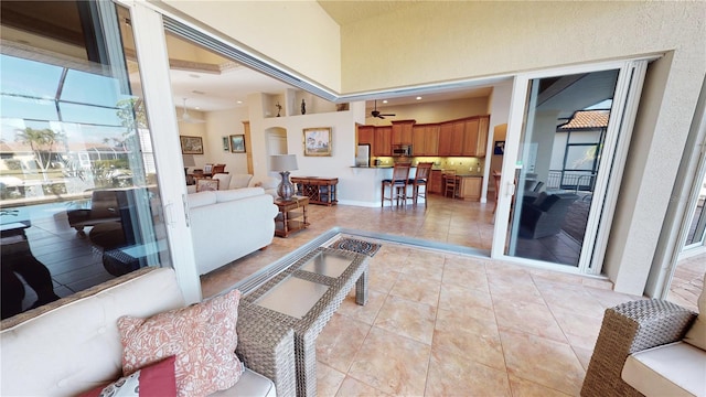 living room featuring ceiling fan, a towering ceiling, and light tile patterned floors