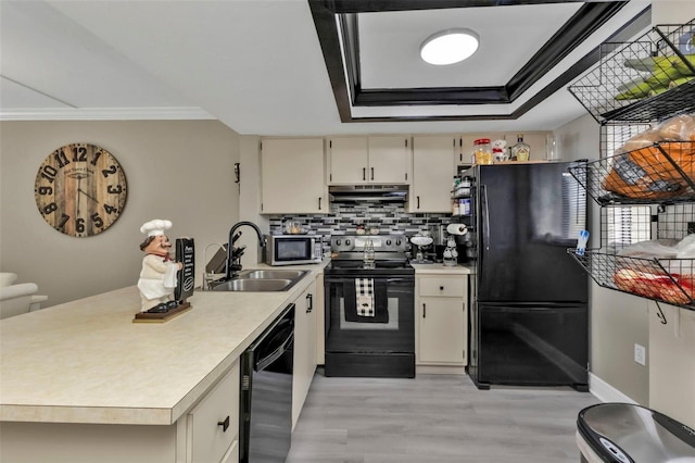 kitchen featuring black appliances, sink, a tray ceiling, crown molding, and cream cabinetry