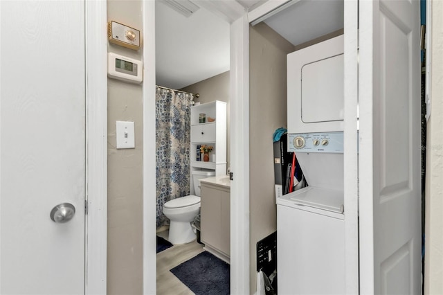 bathroom with vanity, toilet, wood-type flooring, and stacked washer / dryer