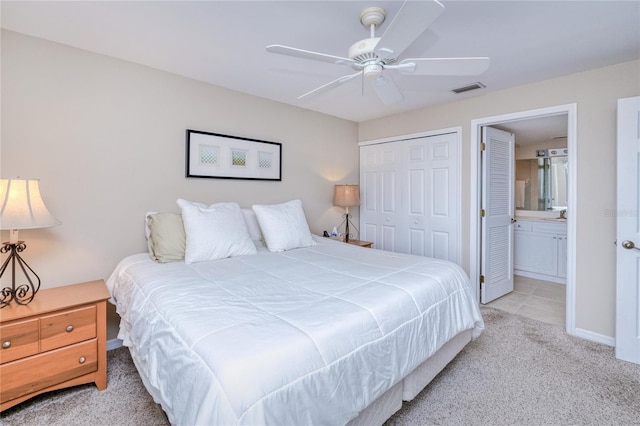 carpeted bedroom featuring a closet, ensuite bathroom, and ceiling fan