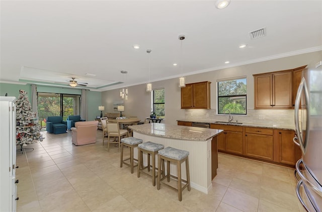 kitchen with ceiling fan, a kitchen island, stainless steel appliances, and a wealth of natural light