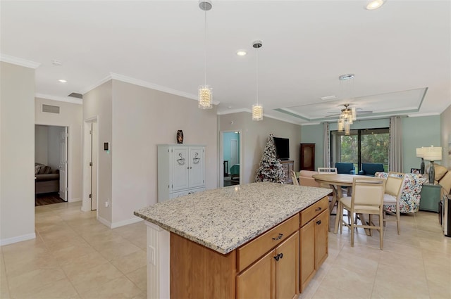 kitchen with light stone countertops, ornamental molding, ceiling fan, decorative light fixtures, and a kitchen island