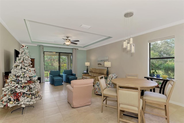 tiled living room featuring ceiling fan, a healthy amount of sunlight, ornamental molding, and a tray ceiling