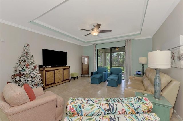 tiled living room with ceiling fan, ornamental molding, and a tray ceiling