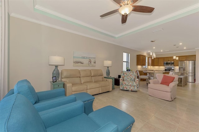 living room featuring ceiling fan, ornamental molding, light tile patterned floors, and a tray ceiling