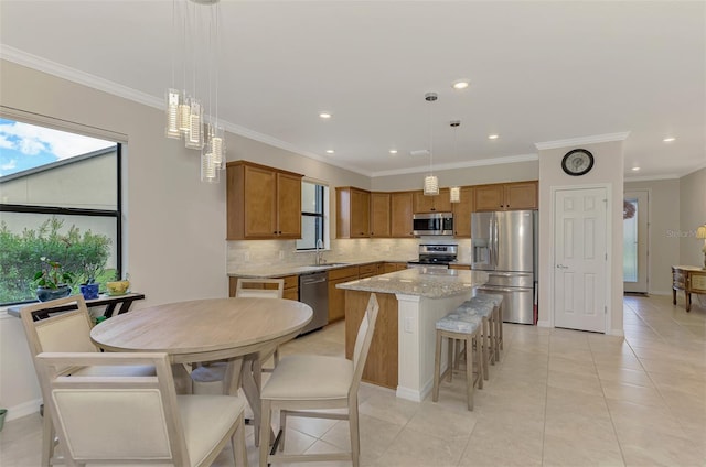 kitchen with tasteful backsplash, a kitchen island, stainless steel appliances, and decorative light fixtures