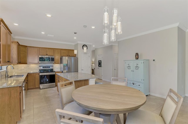 kitchen featuring light stone countertops, sink, decorative light fixtures, a kitchen island, and appliances with stainless steel finishes