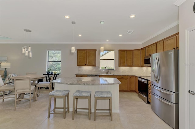 kitchen with hanging light fixtures, a center island, sink, and appliances with stainless steel finishes