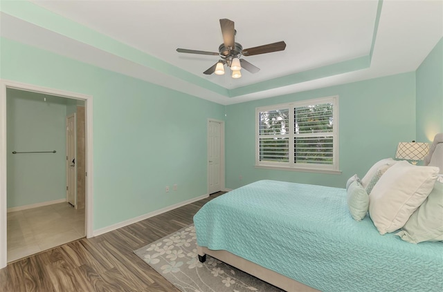 bedroom featuring wood-type flooring, a tray ceiling, and ceiling fan