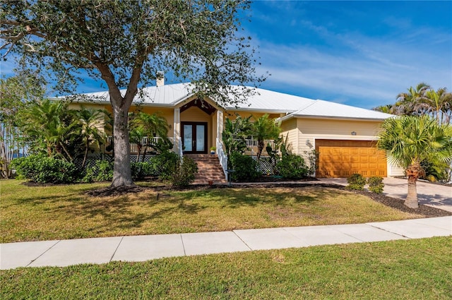 ranch-style house featuring french doors, a garage, covered porch, and a front lawn