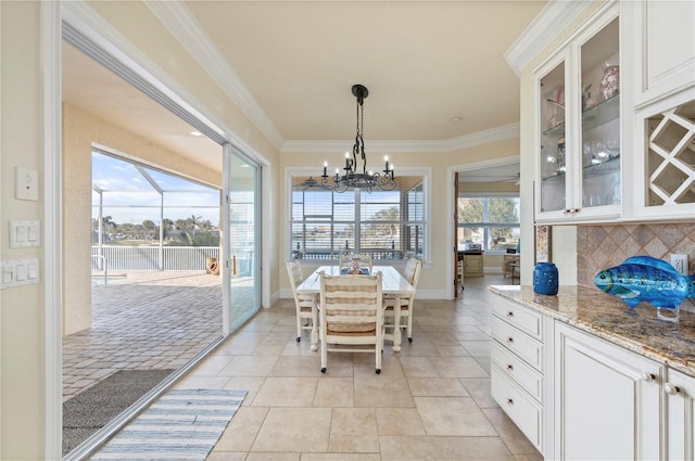 tiled dining space with crown molding and a chandelier