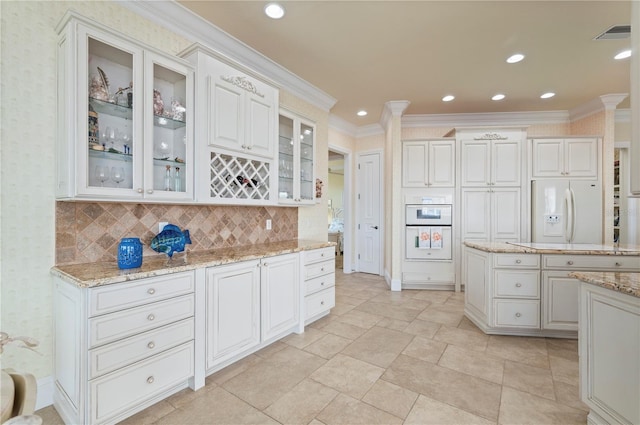 kitchen with white cabinetry, light stone countertops, and white appliances